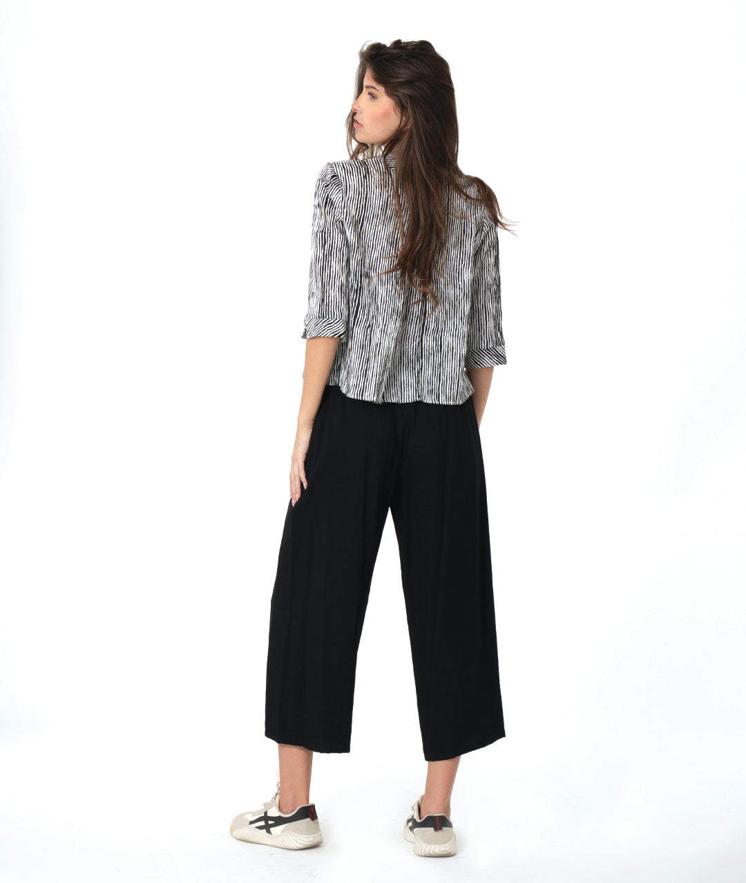 model in a wide leg black pant with a split at the ankle front, worn with a black and white striped blouse with 3/4 sleeves and a twin button detail