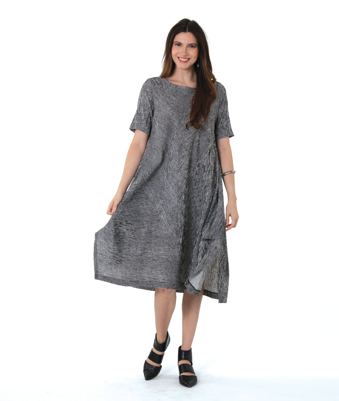 model in a black and white striped dress with contrasting panels of directional stripes. Dress has a round neckline, elbow length sleeves and splits and tucks at the sides