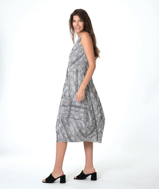 Woman wearing a sleeveless black and white striped dress with varying directional panels