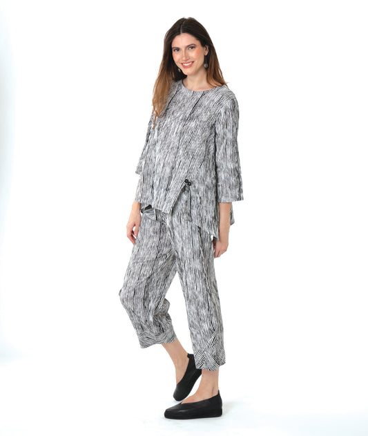 model in a wide leg black and white striped pant with a tapered ankle, worn with a matching pullover blouse with front splits and a double button detail