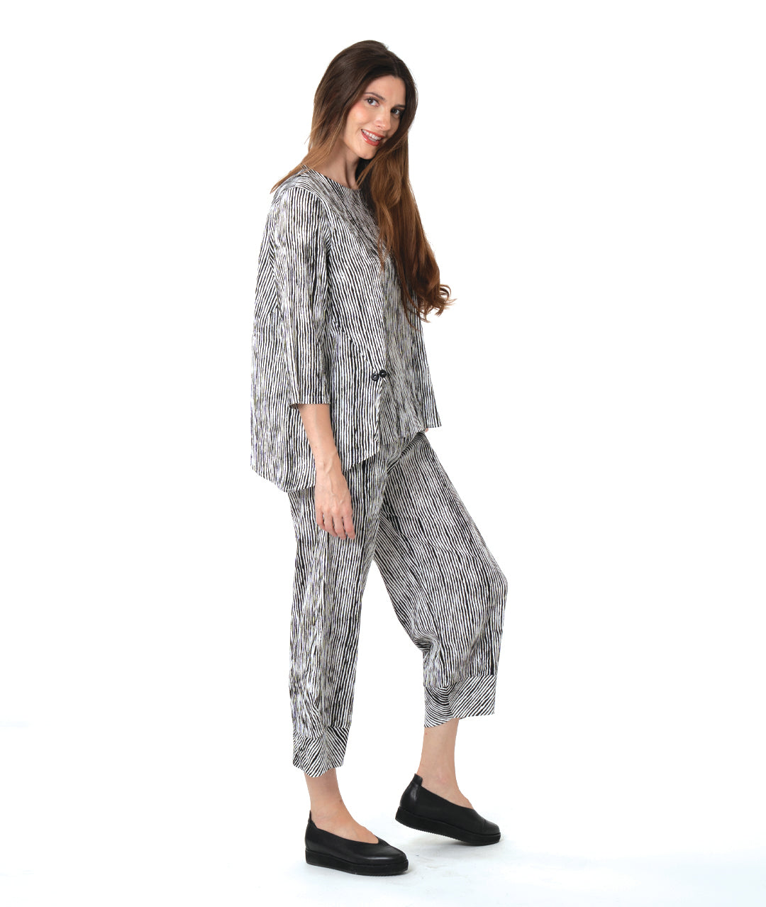 model in a wide leg black and white striped pant with a tapered ankle, worn with a matching pullover blouse with front splits and a double button detail