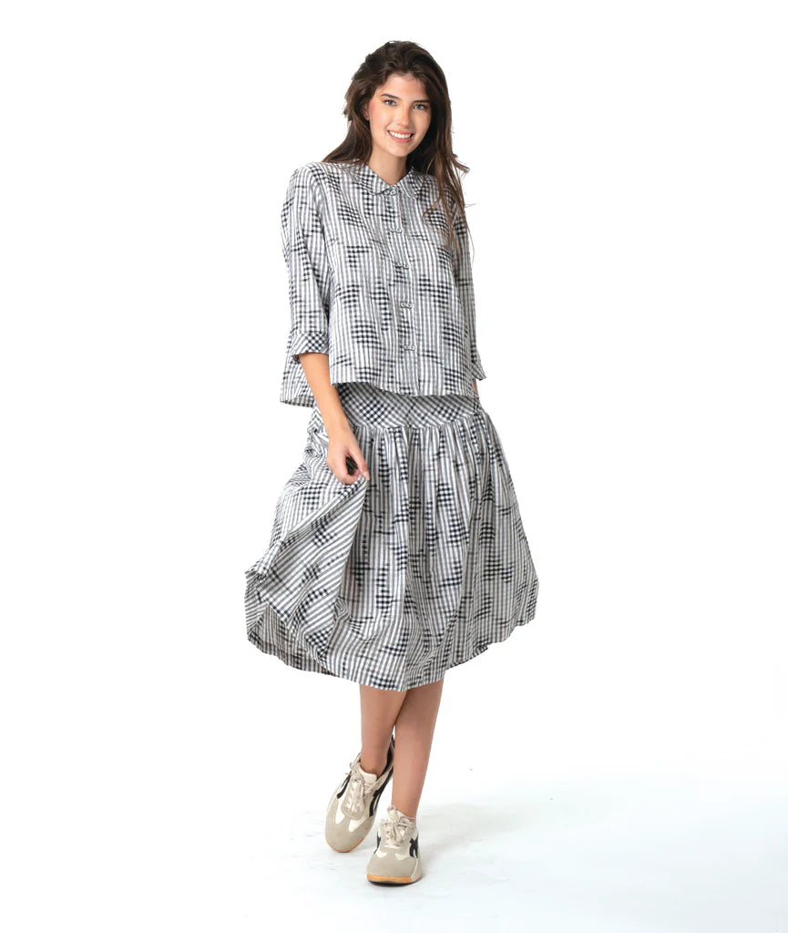 Woman wearing a black and white patterned shirt and skirt on a white background