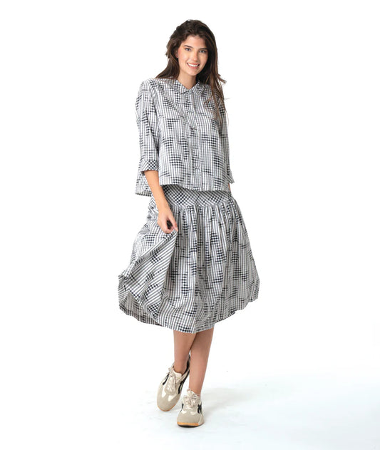 Woman wearing a black and white patterned shirt and skirt on a white background