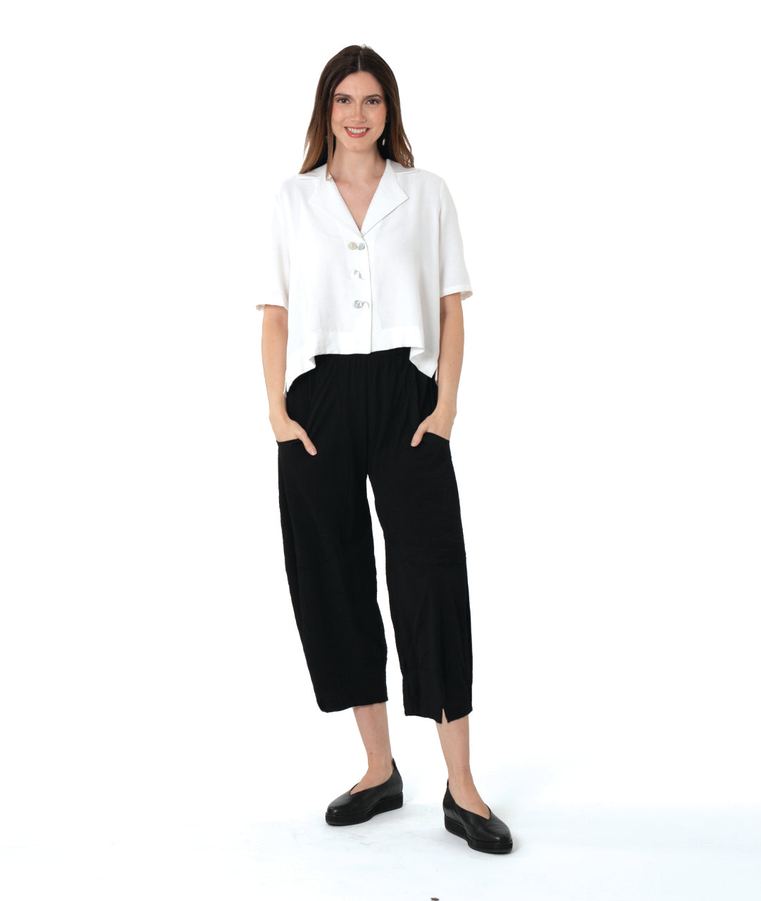 model in a cropped black pant with a boxy button down with an elbow length sleeve and an open collar