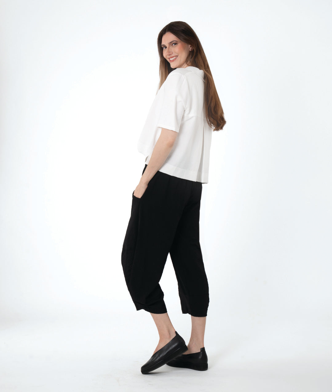 model in a cropped black pant with a boxy button down with an elbow length sleeve and an open collar