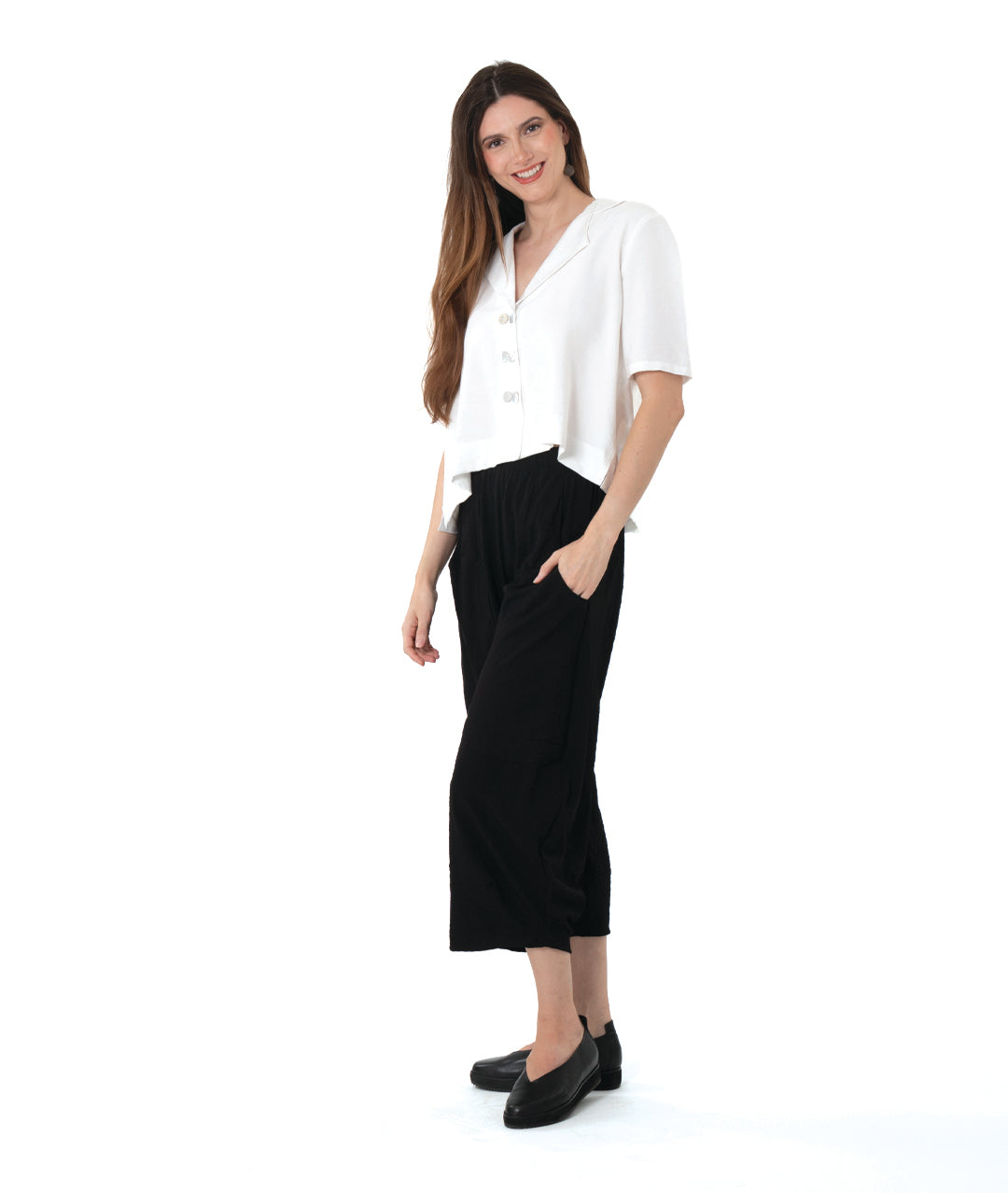 model in a cropped black pant with a boxy button down with an elbow length sleeve and an open collar