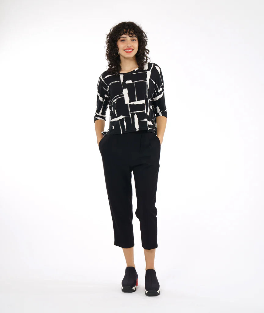 model wearing black and white print top with boxy cut and dolman sleeves paired with black pants and sneakers