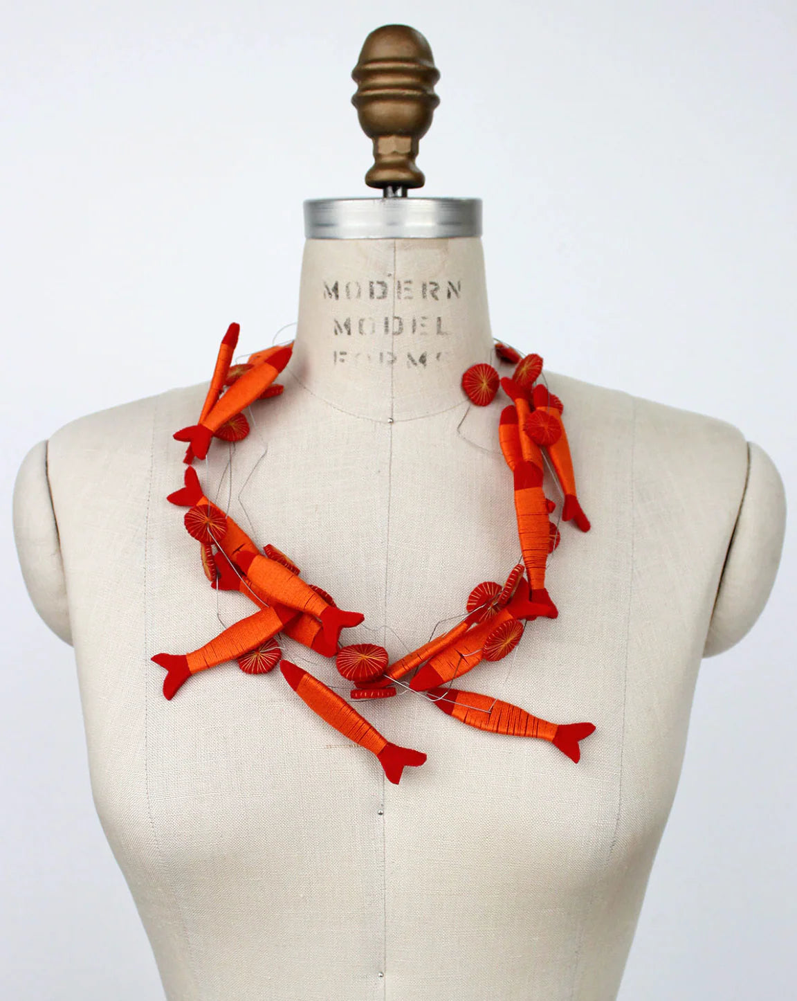 Orange fish necklace on a mannequin with a white background