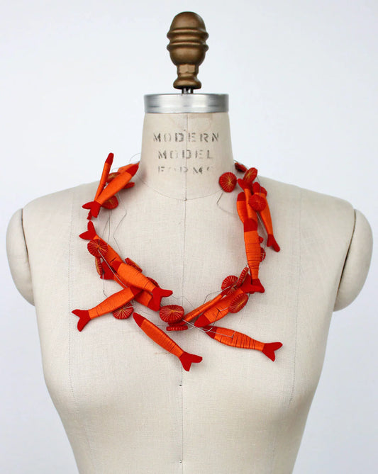 Orange fish necklace on a mannequin with a white background
