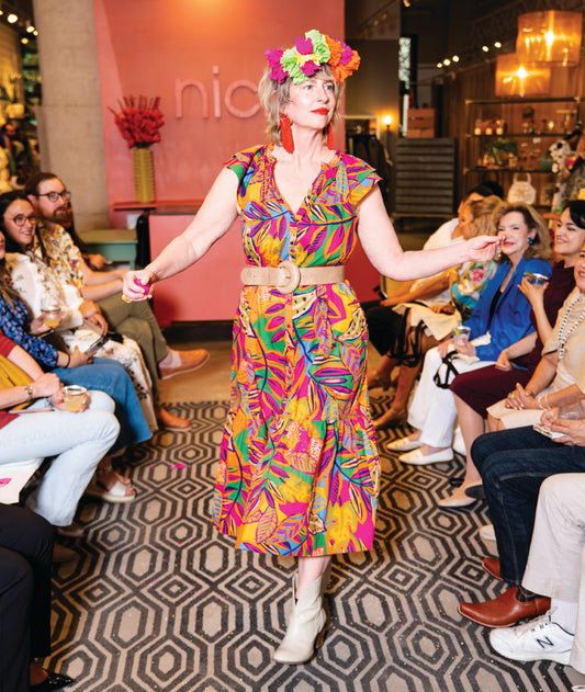model in a midi length tropical print dress with a ruffled neckline and buttons at the center front