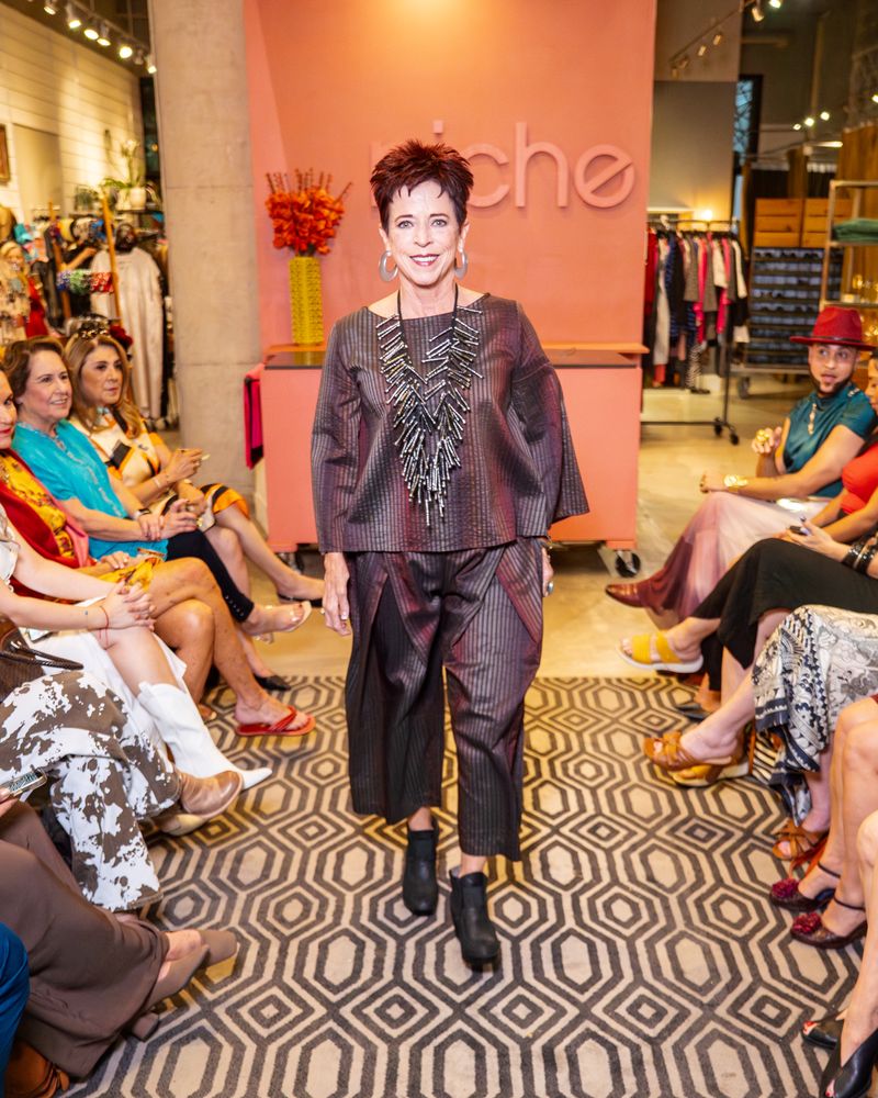 model in matching shimmer brown stripe outfit with statement necklace walking down runway