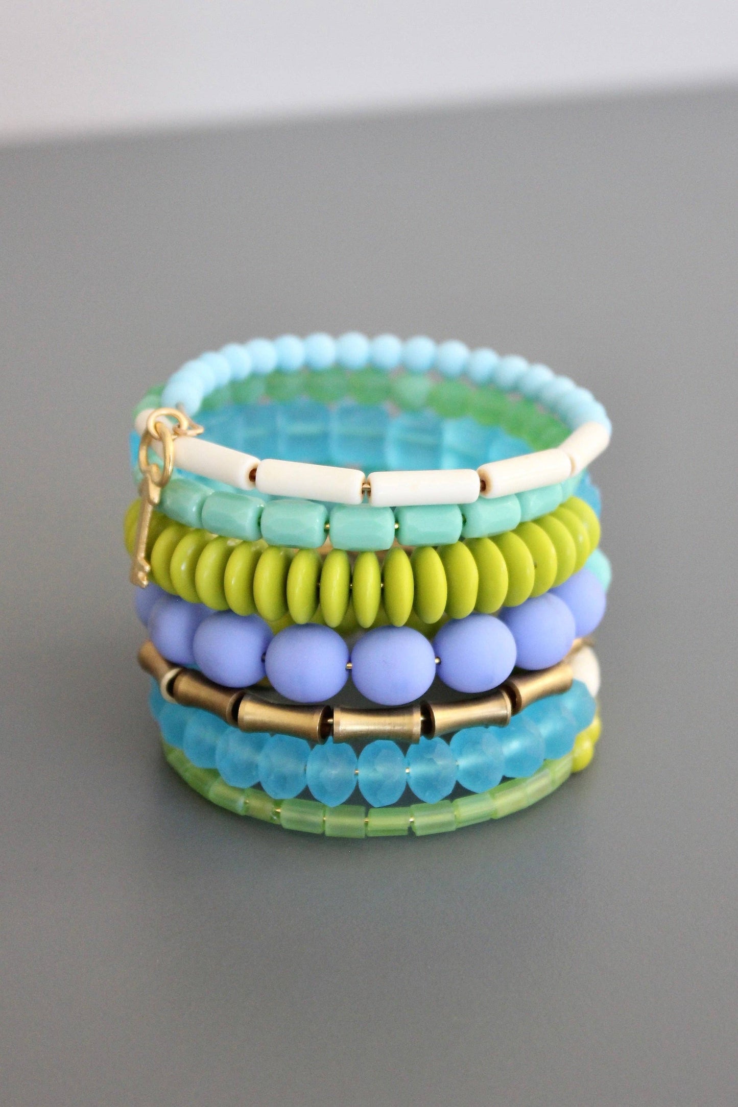 Stack of colorful beaded bracelets on a gray surface