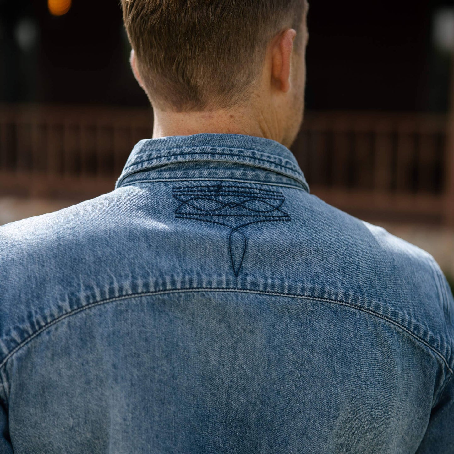 model showing back stitching detail of denim long sleeve.