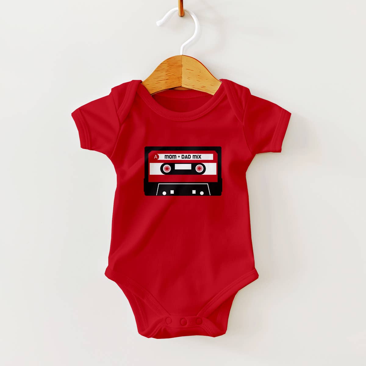 Red baby onesie with a cassette tape design on a hanger against a white background