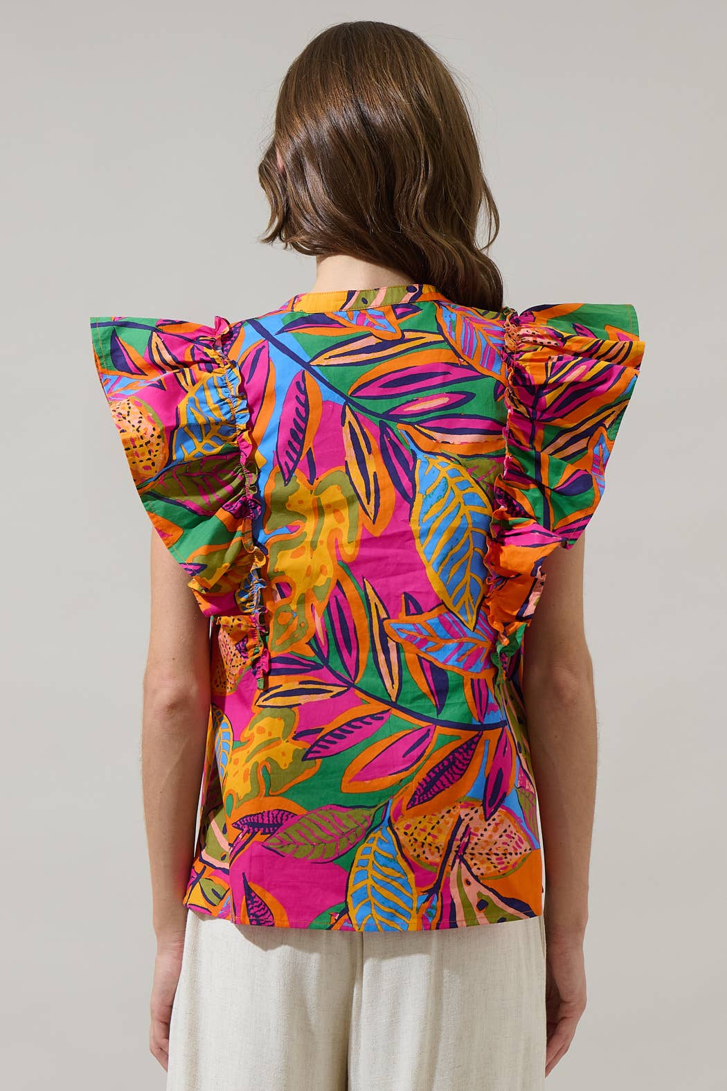 model in a multi color tropical print blouse with a white pant