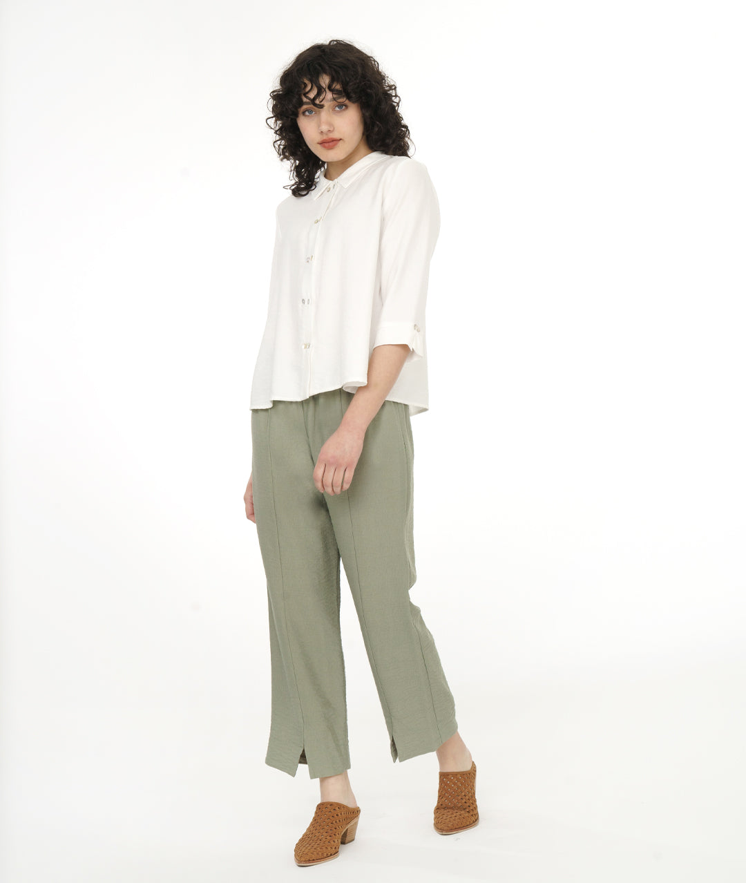 model in a white button down blouse with a soft moss green straight leg, elastic waist pant with center front side seams ending in a split at either ankle