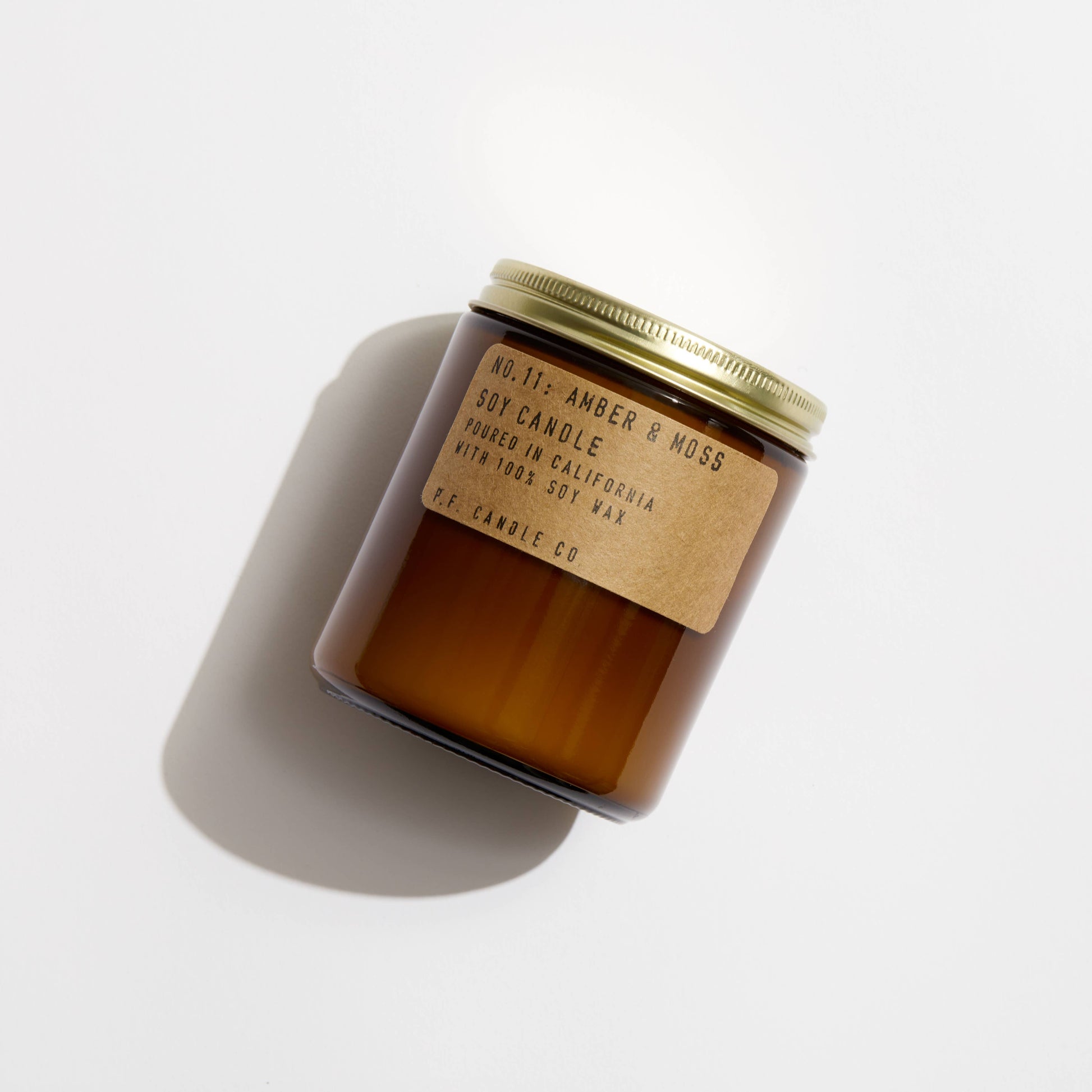Brown candle with a gold lid on a white background