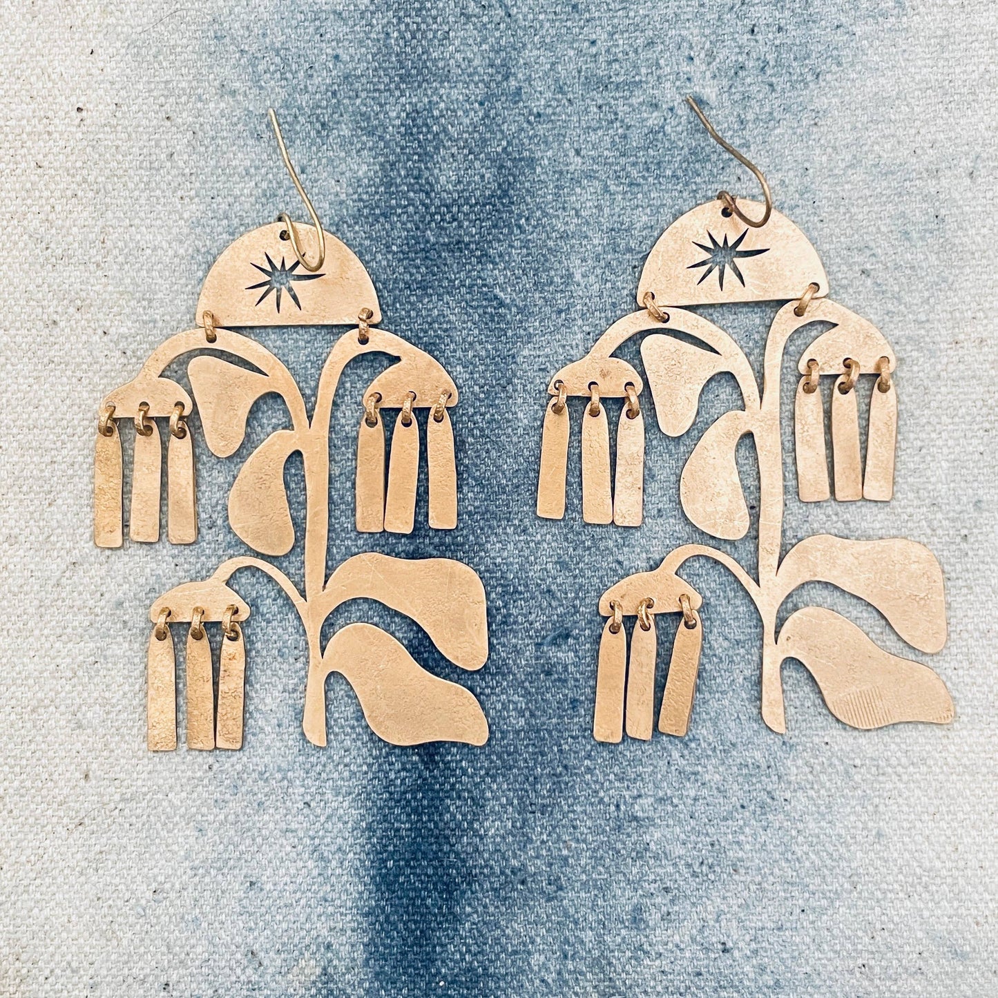 Pair of gold floral earrings on a denim background