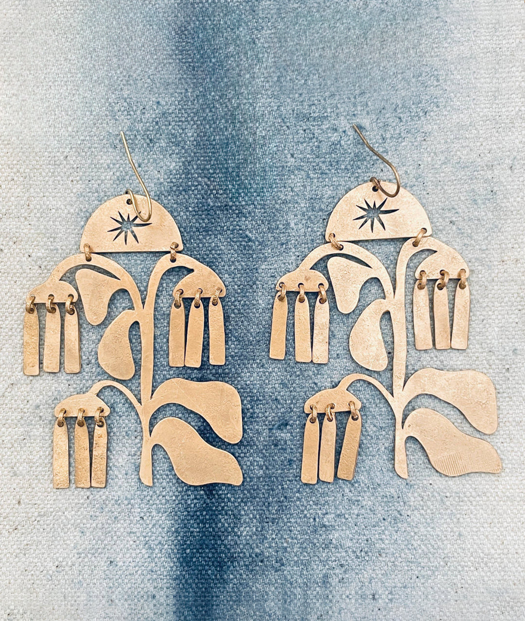 Pair of gold floral earrings on a denim background