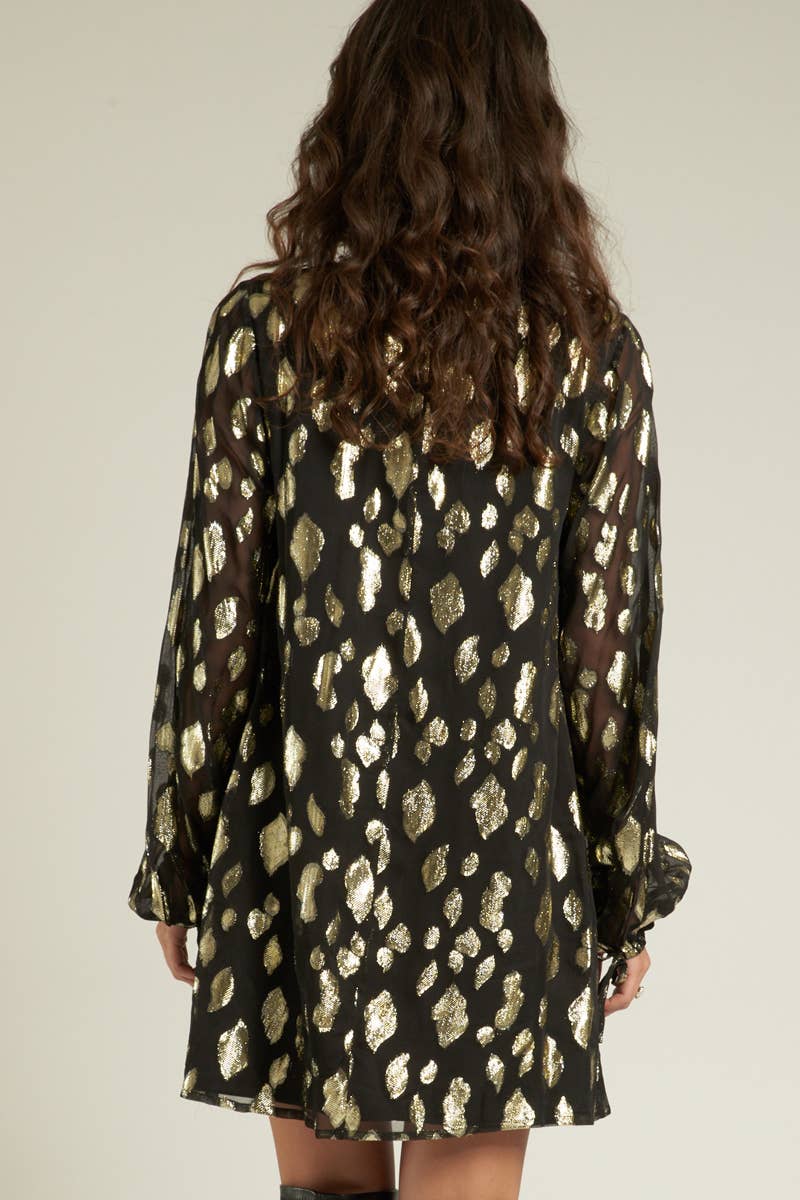 back view of a model wearing a black long sleeved dress with gold sparkly spots