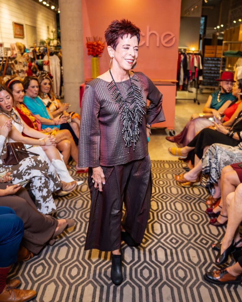 model in matching shimmer brown stripe outfit with statement necklace walking down runway