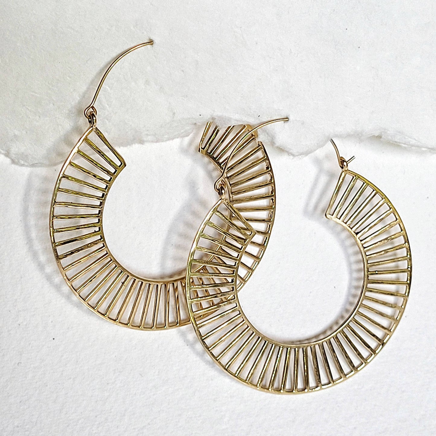 brass hoop earrings hook closure and spindle design on white background