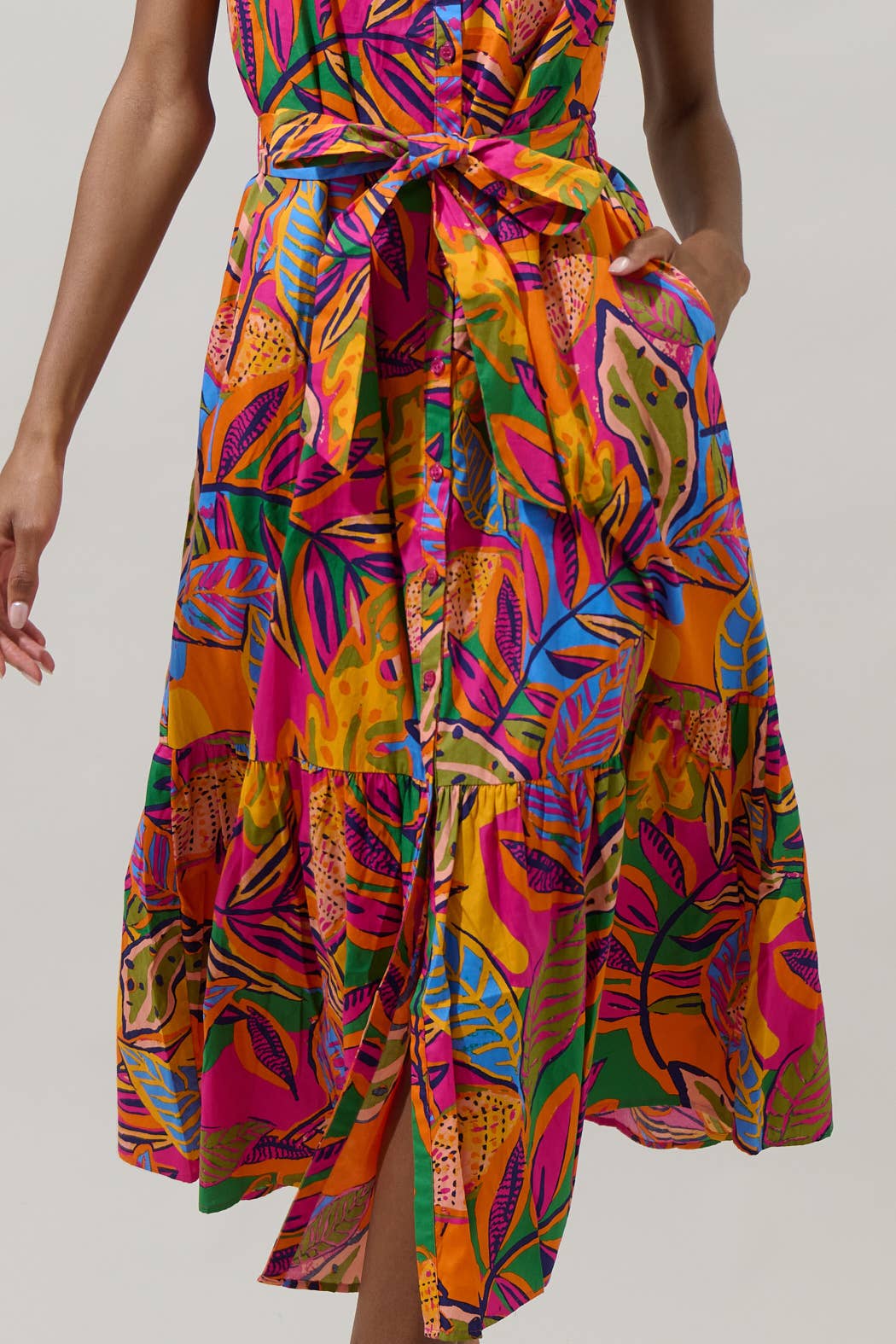 model in a midi length tropical print dress with a ruffled neckline and buttons at the center front