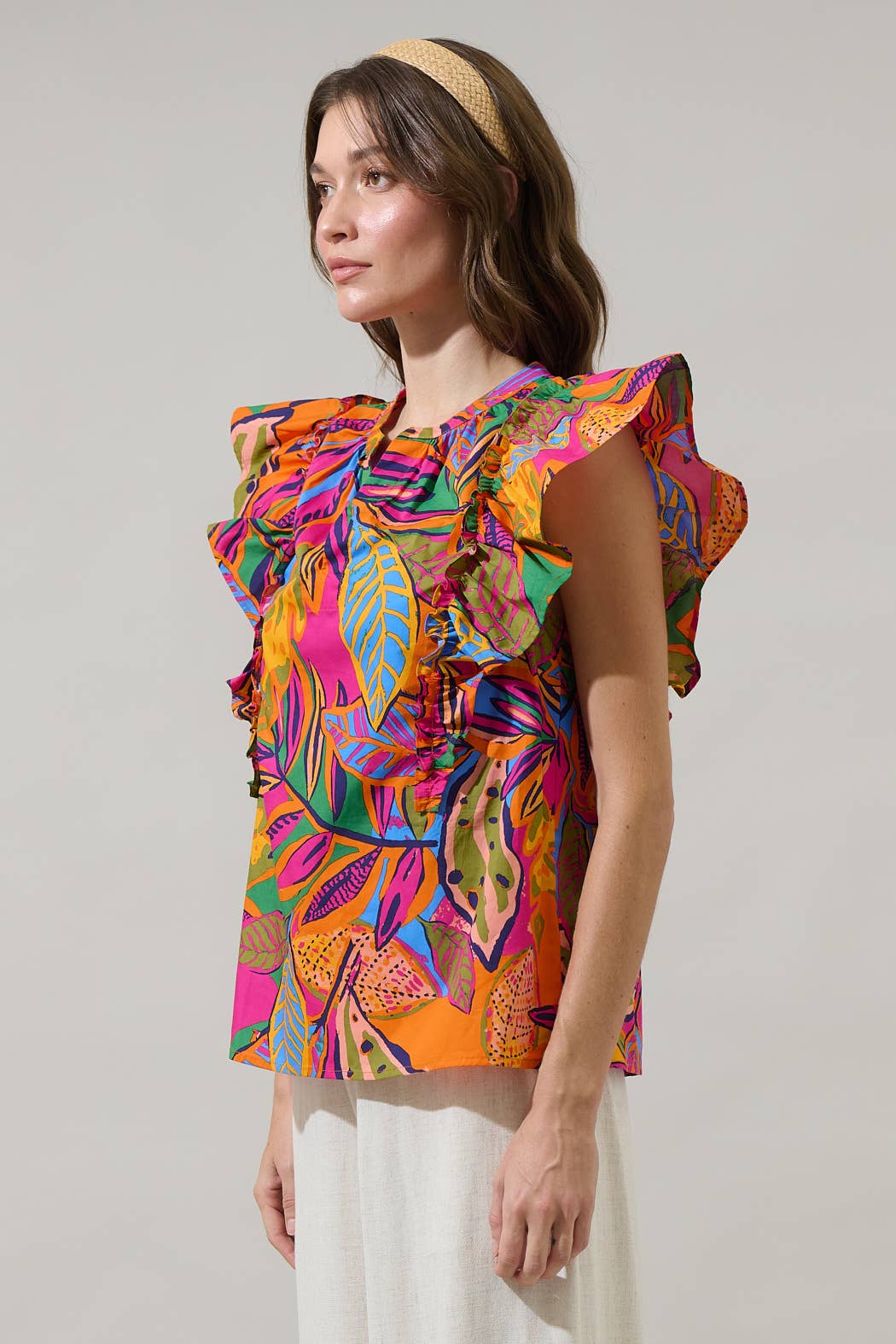 model in a multi color tropical print blouse with a white pant