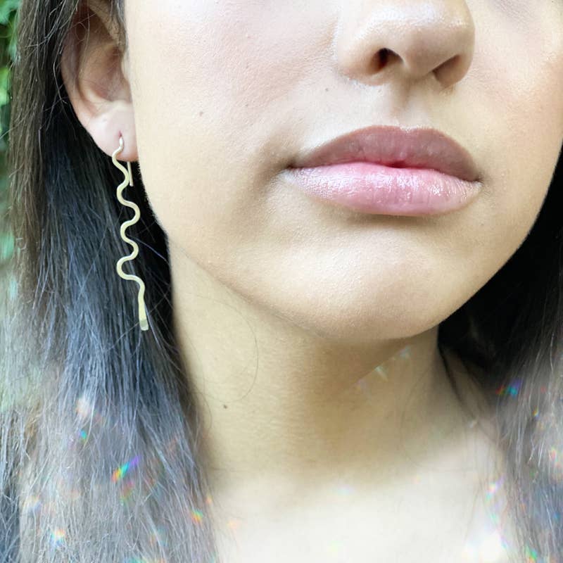 silver earrings feature a unique, dangly design. close up on brunette model