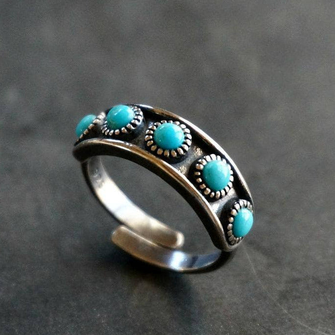 Silver ring with turquoise stones on a gray background