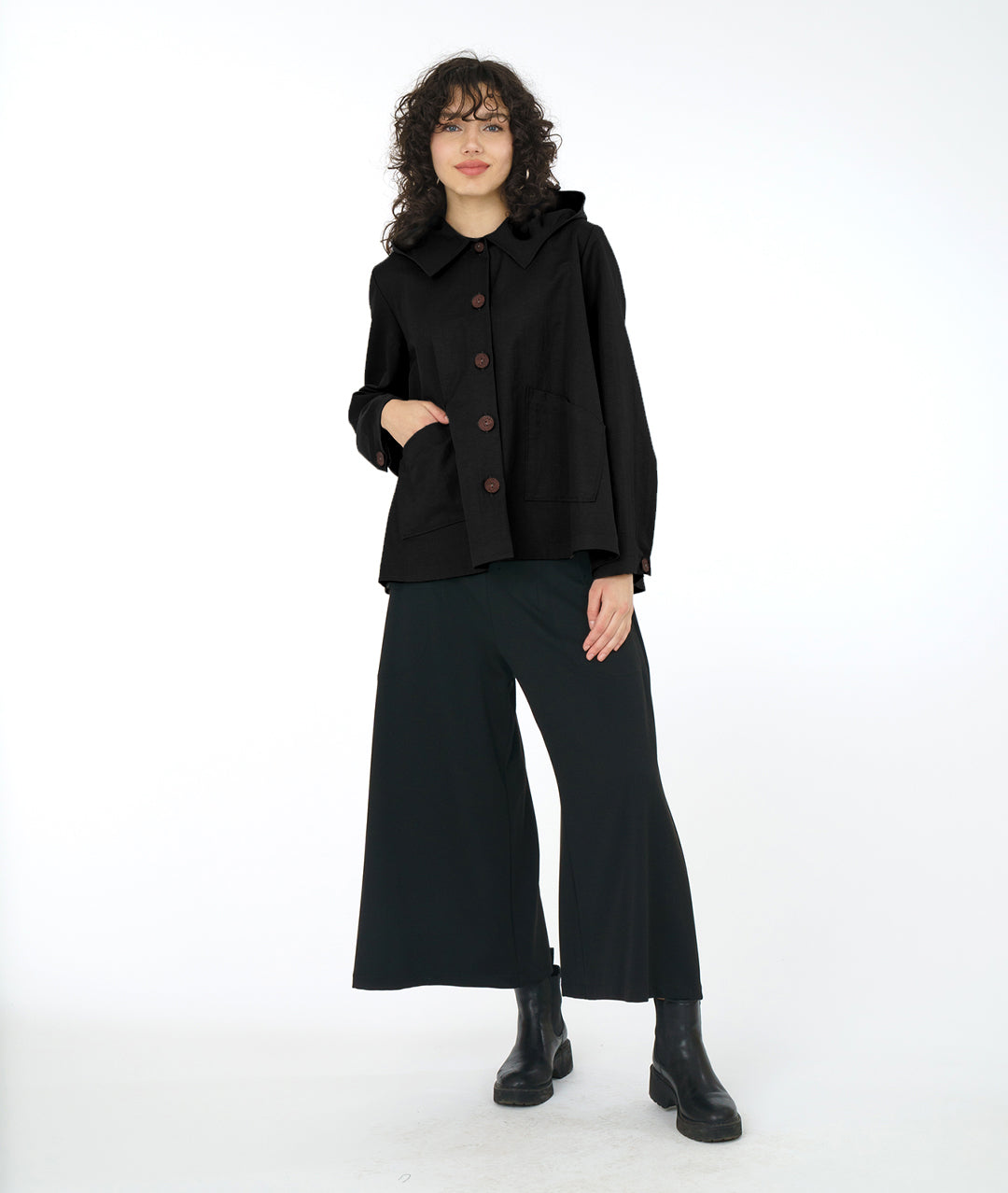model in a wide leg black pant with a black, full bodied short jacket with a hood