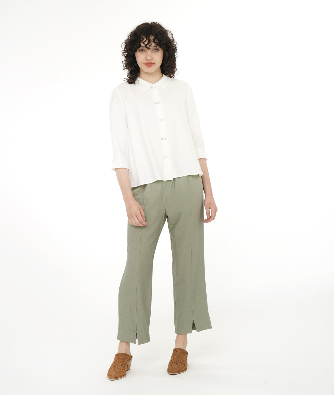 model in a white button down blouse with a soft moss green straight leg, elastic waist pant with center front side seams ending in a split at either ankle