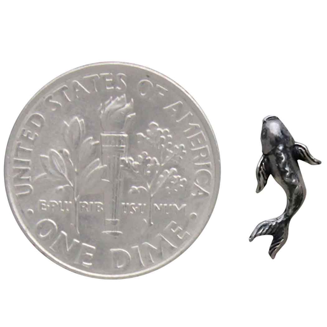 Small silver fish figurine next to a U.S. dime for scale.