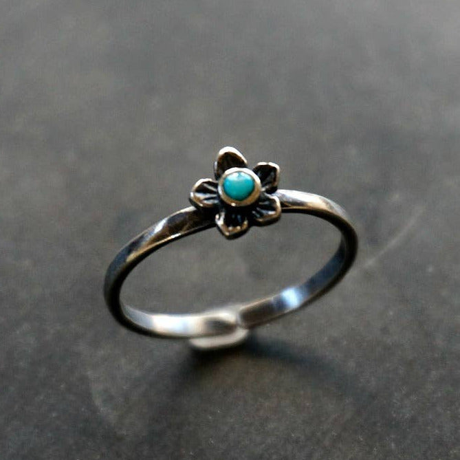 Silver ring with a turquoise stone on a gray background