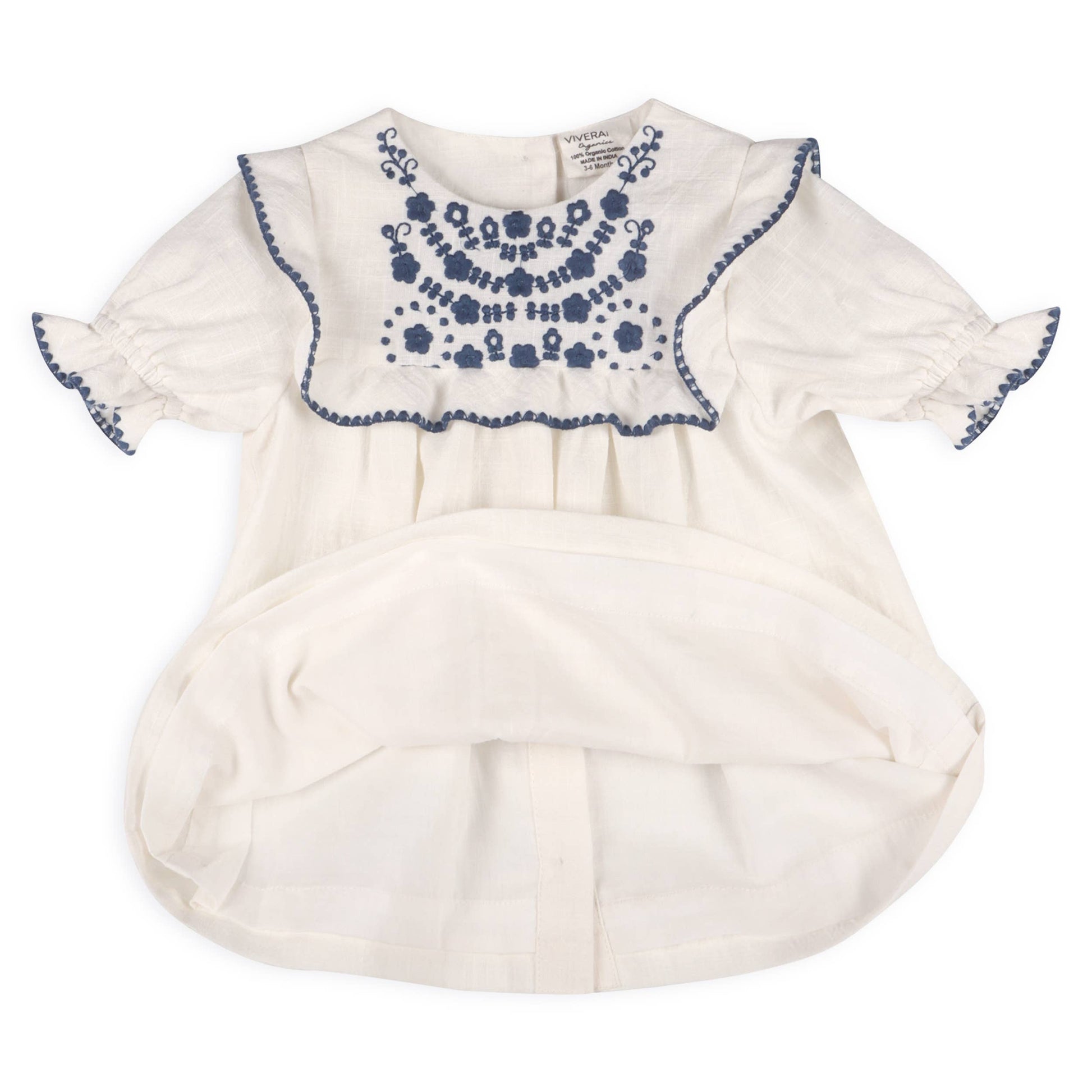 showing lining of off white baby top with blue floral embroidery design