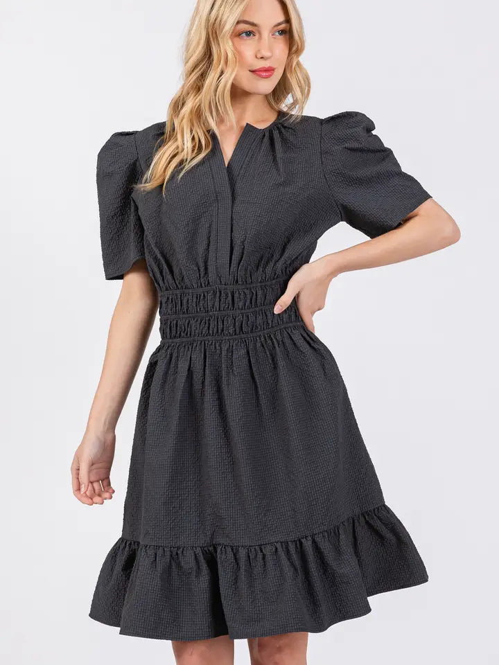 model wearing black puff sleeved ruffle dress