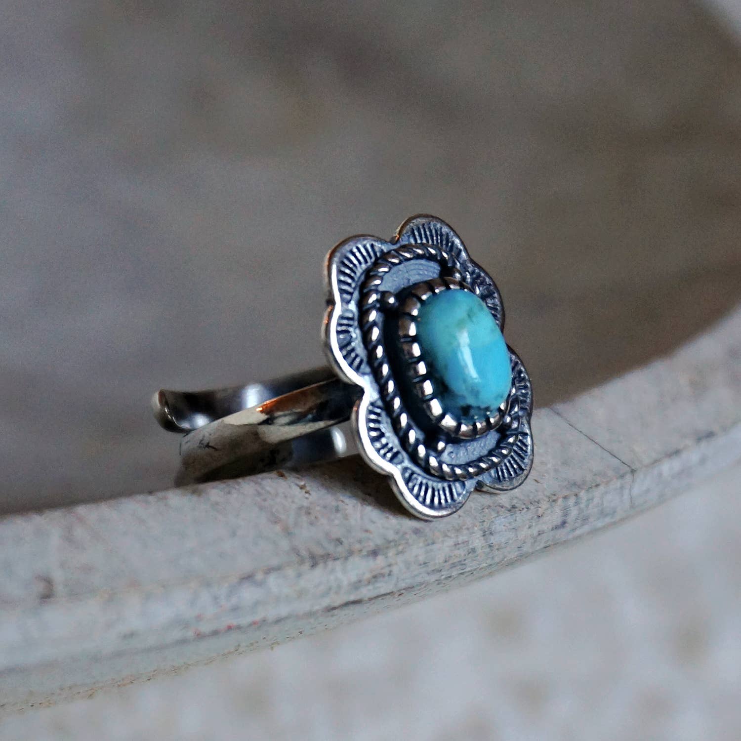 Silver ring with a turquoise stone on a wooden surface