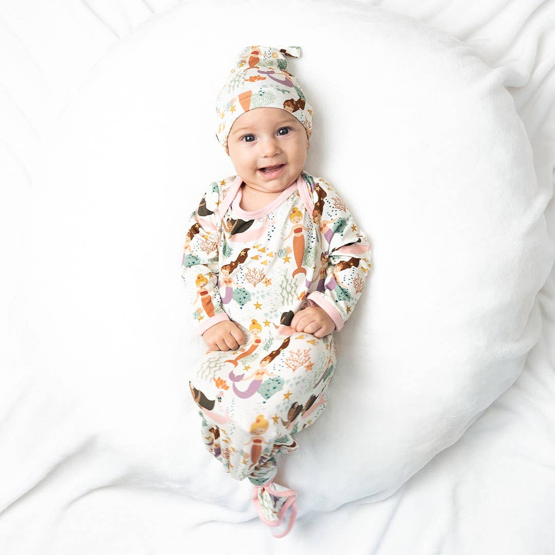 Baby wrapped in a patterned swaddle and wearing a matching hat on a white background