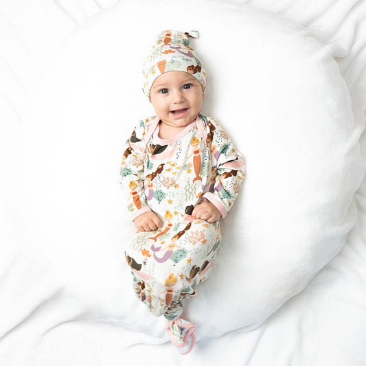 Baby wrapped in a patterned swaddle and wearing a matching hat on a white background