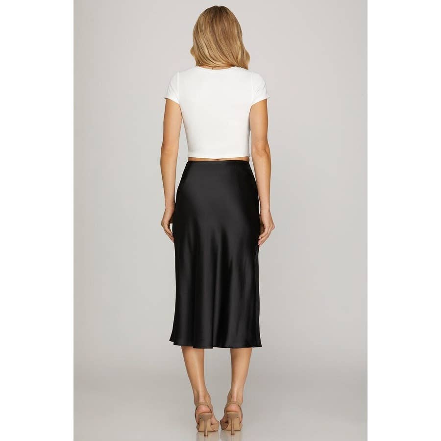 Woman wearing a white top and black skirt on a plain background