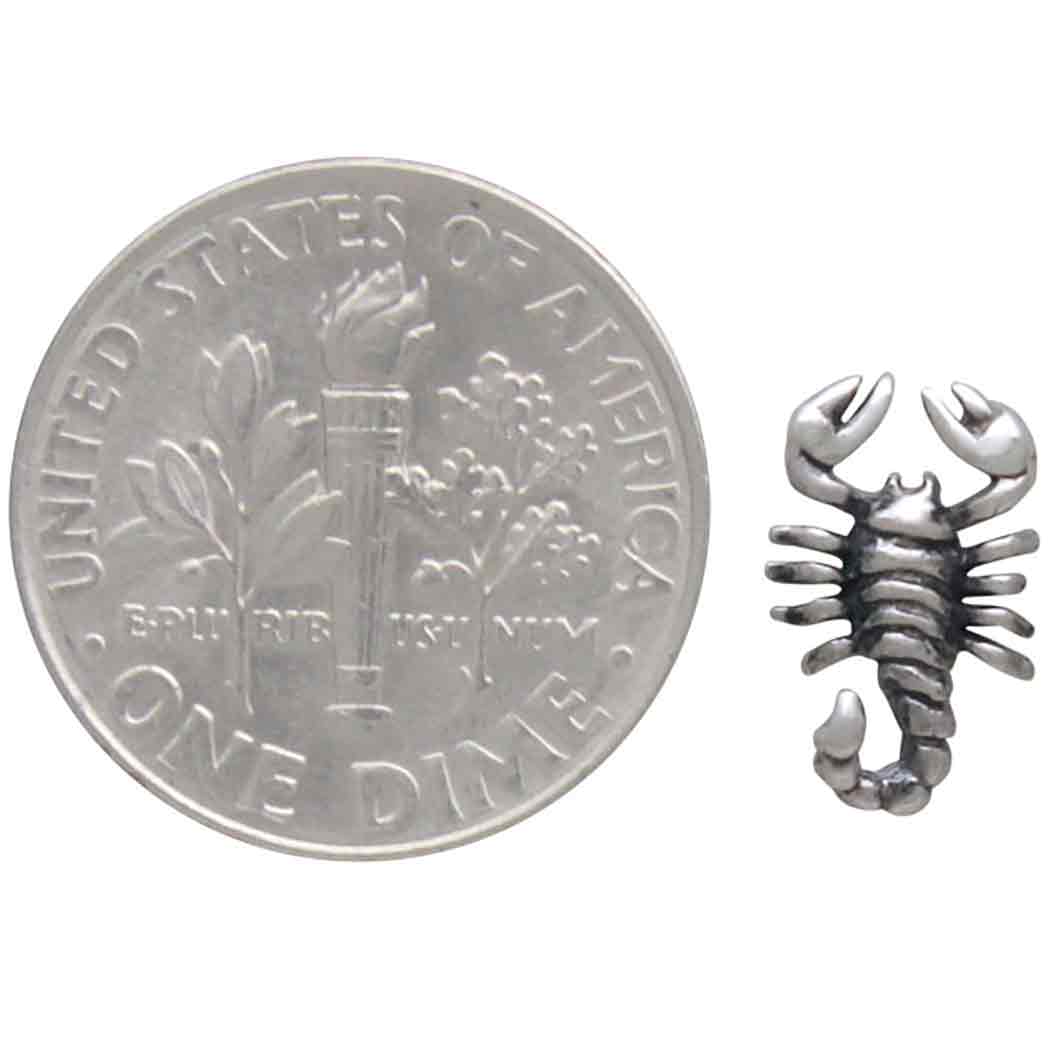 scorpion earring next to a us dime for size