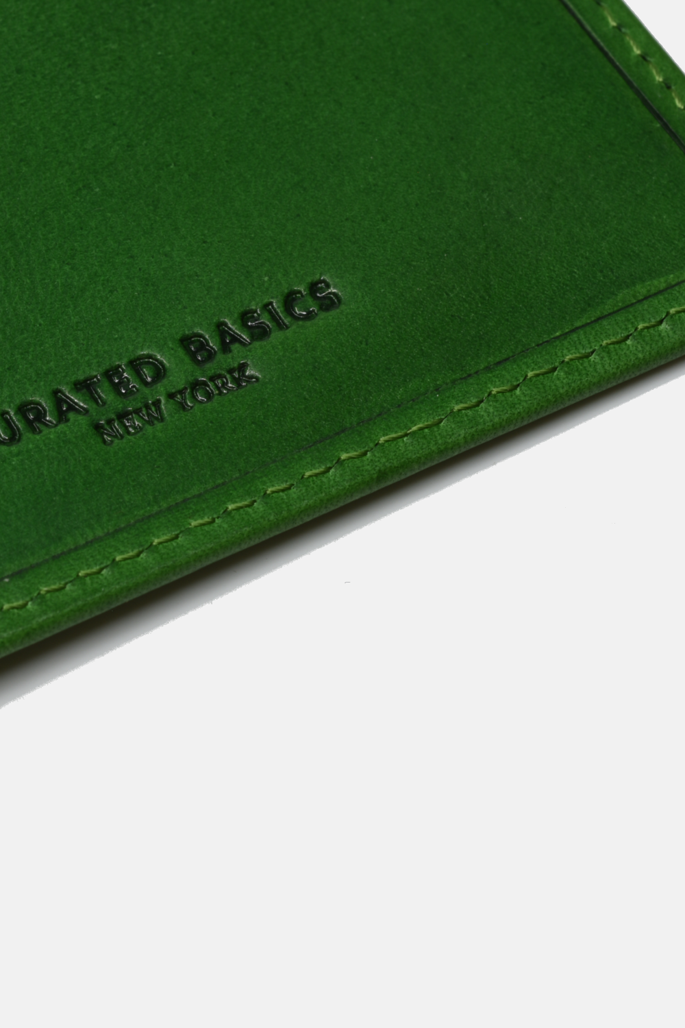 close-up of green wallet with "curated basics new york" logo