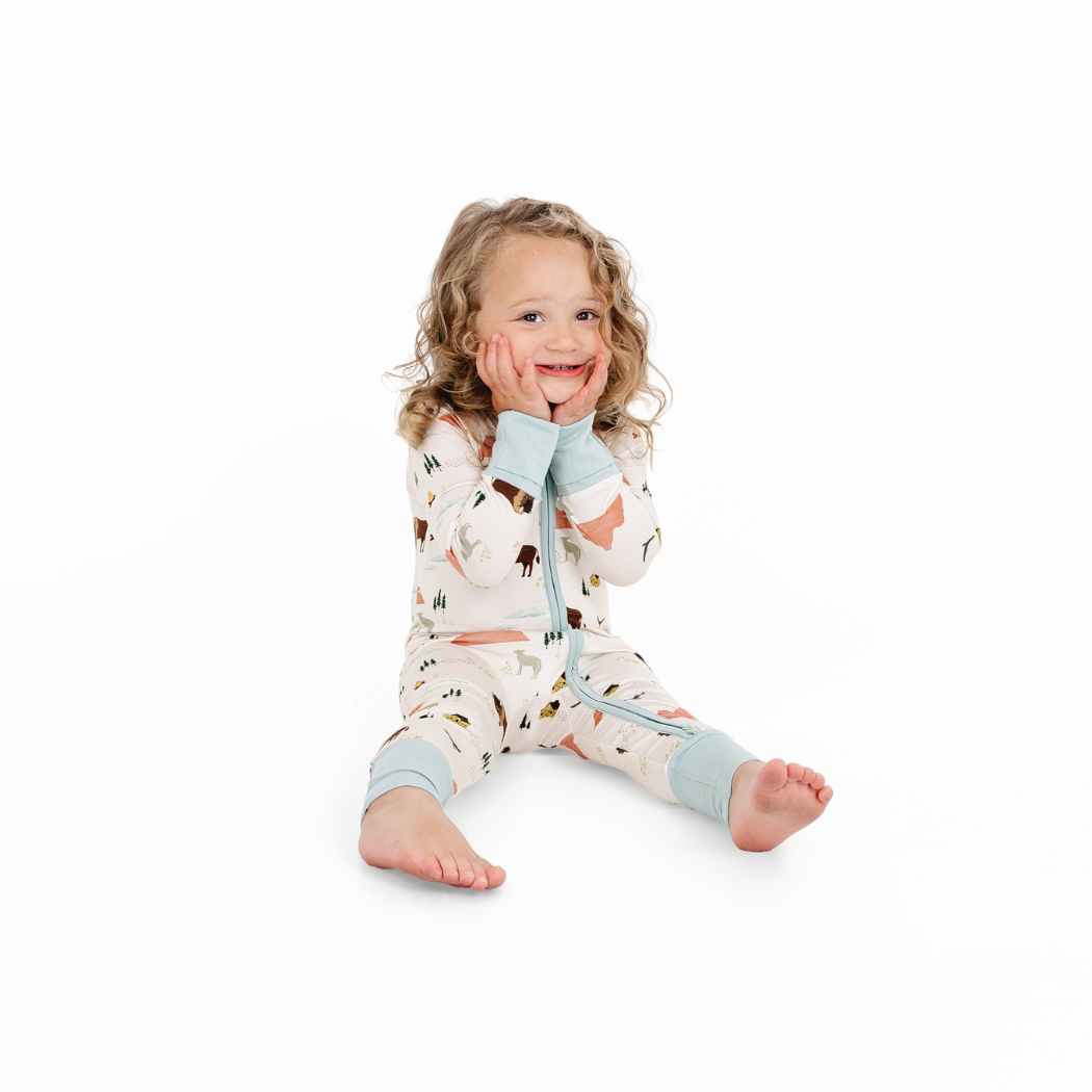 Child wearing a patterned onesie with light blue accents on a white background