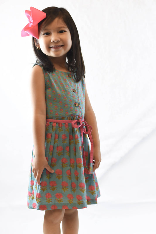 Young girl wearing a patterned dress with a pink bow on a white background