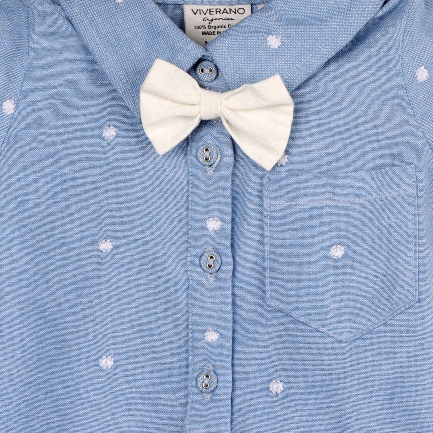 close up of white bow tie on light blue baby jumper with white dots, collar and button up