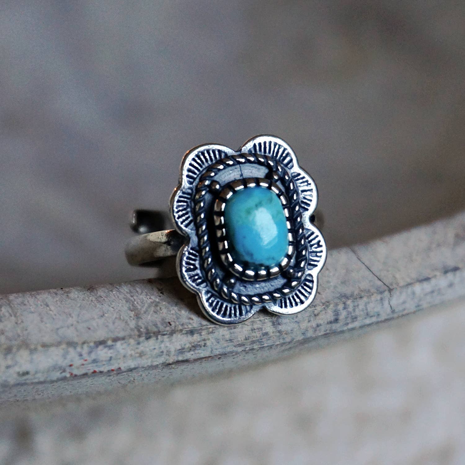 Silver ring with a blue stone on a textured surface