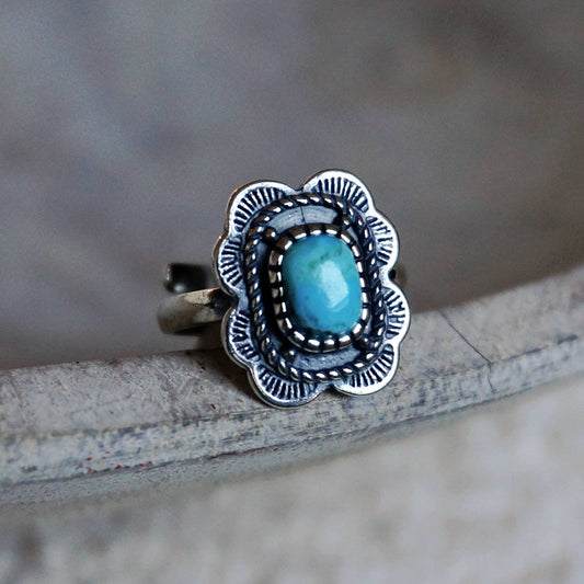 Silver ring with a blue stone on a textured surface