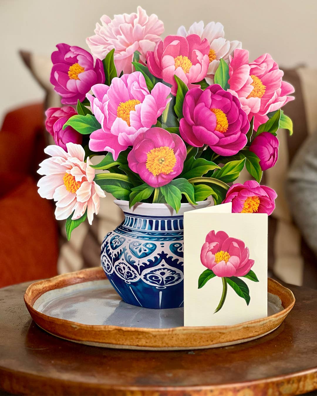 Bouquet of pink and purple flowers in a blue and white vase on a wooden tray.