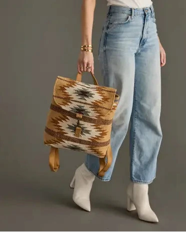Woman holding a patterned bag against a plain background