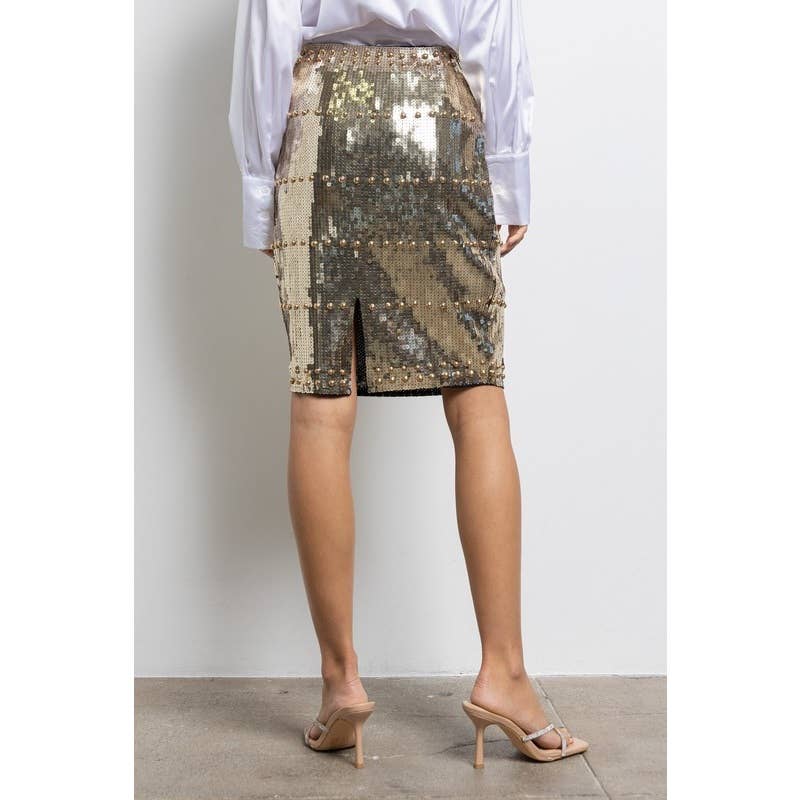 Person wearing a gold sequin skirt with a plain background